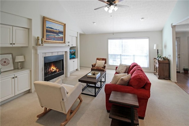 living area with a fireplace, lofted ceiling, light colored carpet, ceiling fan, and a textured ceiling