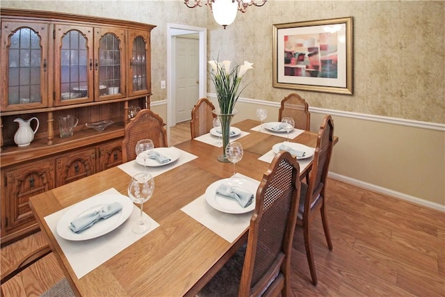 dining space with an inviting chandelier, baseboards, and wood finished floors