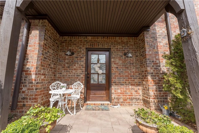 entrance to property featuring a patio and brick siding