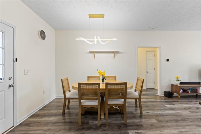 dining space featuring a textured ceiling, dark hardwood / wood-style floors, and a notable chandelier