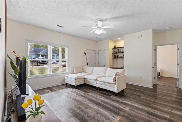 living room featuring ceiling fan, dark hardwood / wood-style flooring, and a textured ceiling