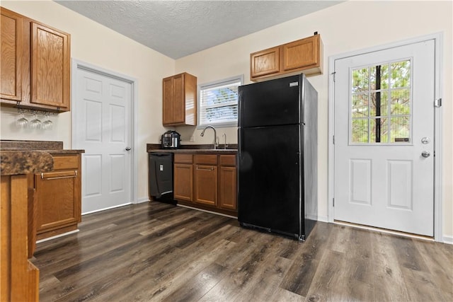 kitchen with a textured ceiling, a wealth of natural light, black fridge, and dark hardwood / wood-style floors