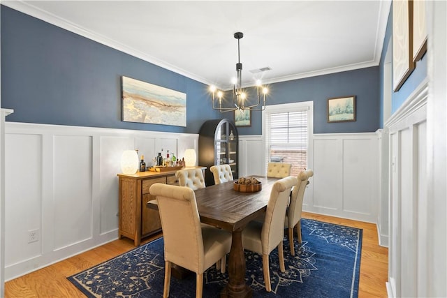 1540 Reynolds Dr, Auburn, AL 36830 - dining space featuring a decorative wall, a wainscoted wall, ornamental molding, a chandelier, and light wood-style flooring