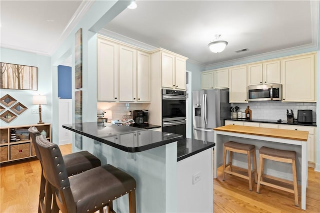 kitchen with tasteful backsplash, a breakfast bar area, stainless steel appliances, and light wood-style flooring