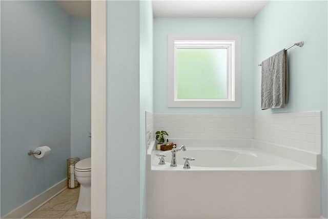 bathroom featuring toilet, baseboards, and a garden tub