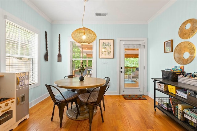 dining area featuring baseboards, ornamental molding, light wood-style flooring, and visible vents