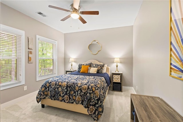 carpeted bedroom with baseboards, a ceiling fan, and visible vents