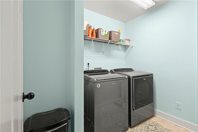 clothes washing area with washer and dryer, laundry area, baseboards, and light tile patterned floors