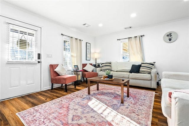 living room featuring dark wood-style flooring, visible vents, and crown molding