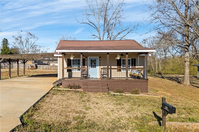 bungalow-style house with concrete driveway, a porch, a carport, and a front yard