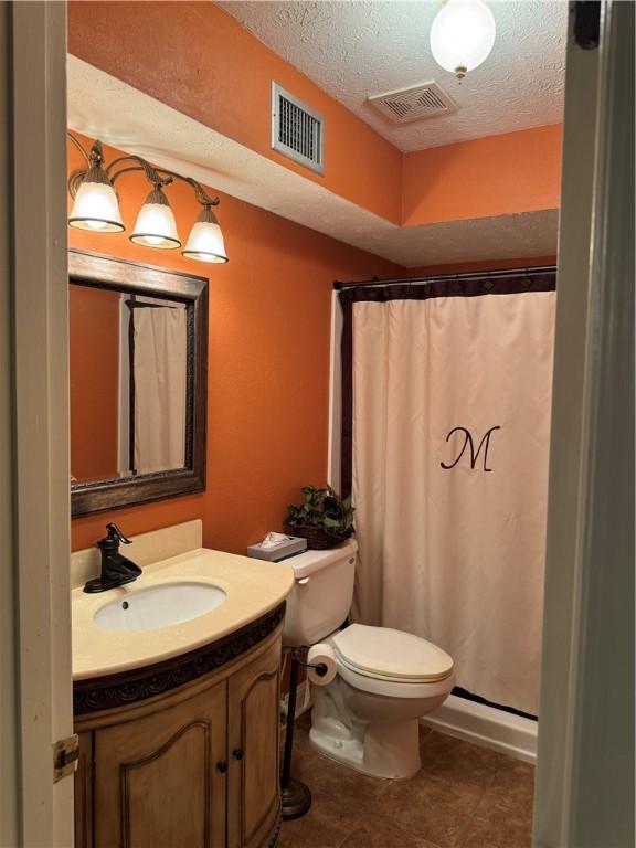 bathroom with a shower with curtain, vanity, a textured ceiling, and toilet