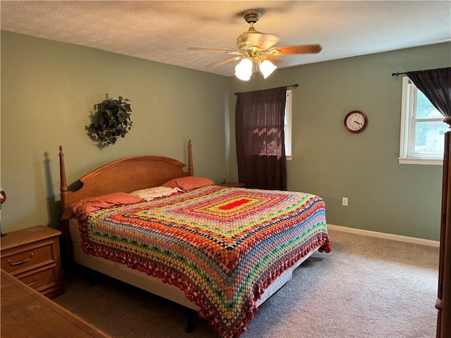 bedroom with ceiling fan, carpet floors, and a textured ceiling