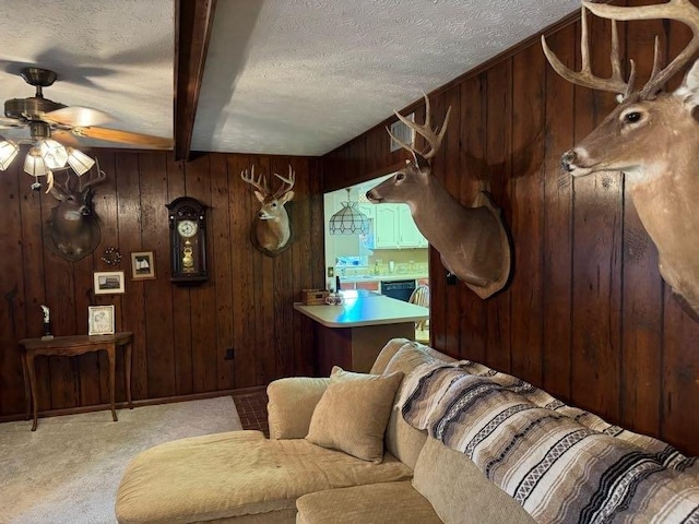 carpeted living room with beamed ceiling, ceiling fan, a textured ceiling, and wooden walls