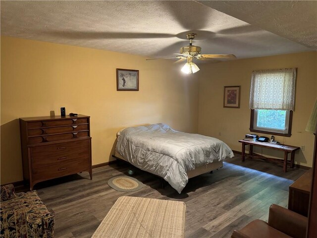 bedroom with a textured ceiling, ceiling fan, and dark wood-type flooring