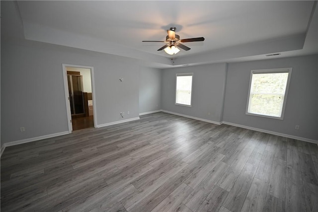 spare room with a raised ceiling, ceiling fan, and hardwood / wood-style floors