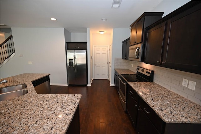 kitchen with decorative backsplash, light stone counters, stainless steel appliances, dark wood-type flooring, and sink