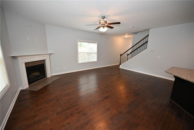 unfurnished living room with a fireplace, dark hardwood / wood-style flooring, and ceiling fan