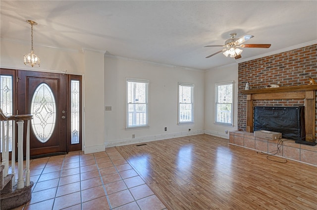 foyer with ornamental molding, a brick fireplace, and a wealth of natural light