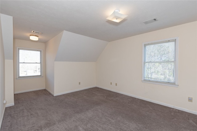 additional living space featuring lofted ceiling and dark carpet