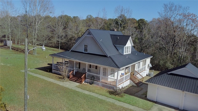 back of house with a garage, a yard, an outdoor structure, and covered porch