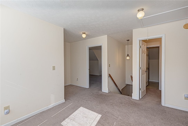 spare room featuring light carpet and a textured ceiling