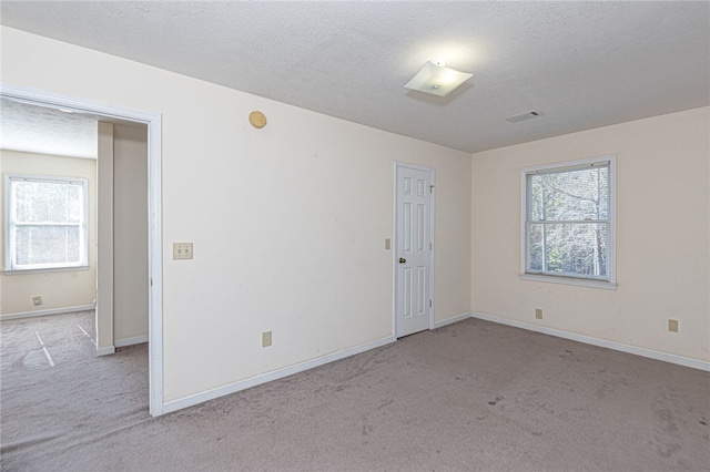 carpeted empty room with a textured ceiling