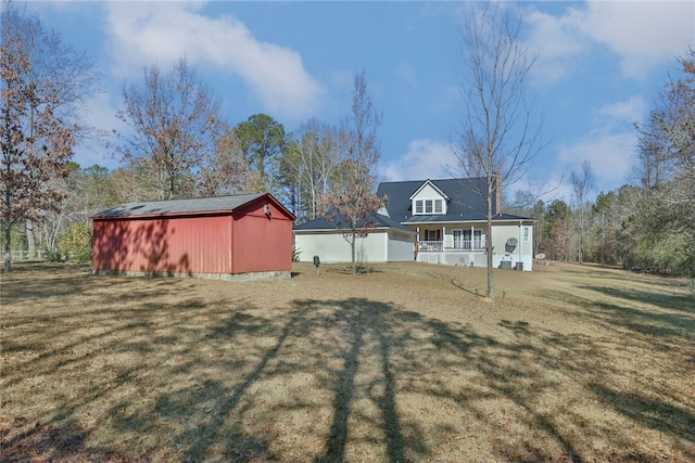 back of house with a yard, an outdoor structure, and a porch