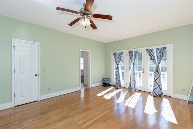 empty room with ceiling fan, light wood-type flooring, and french doors