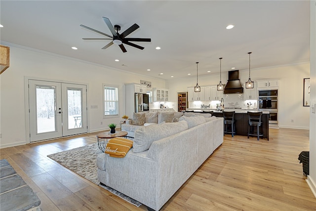 living area featuring light wood finished floors, recessed lighting, ornamental molding, and french doors