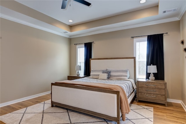 bedroom with multiple windows, a raised ceiling, and visible vents