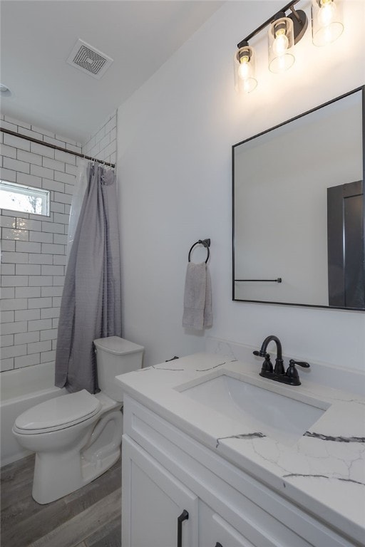 bathroom with visible vents, toilet, wood finished floors, shower / tub combo with curtain, and vanity