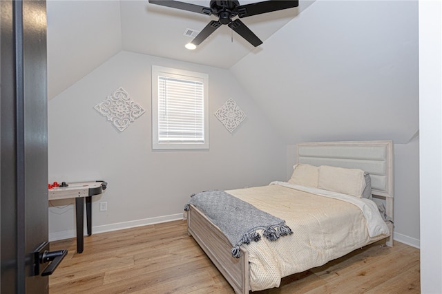 bedroom with visible vents, vaulted ceiling, light wood-style flooring, and baseboards