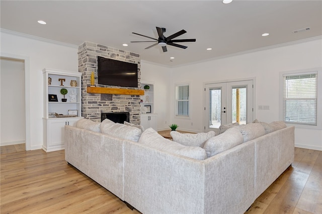 living area featuring ornamental molding, a wealth of natural light, visible vents, and light wood-style floors