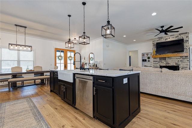 kitchen with an island with sink, open floor plan, decorative light fixtures, dark cabinetry, and stainless steel dishwasher