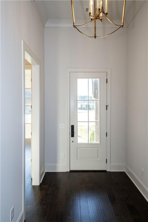 entryway with ornamental molding, dark hardwood / wood-style floors, and a notable chandelier