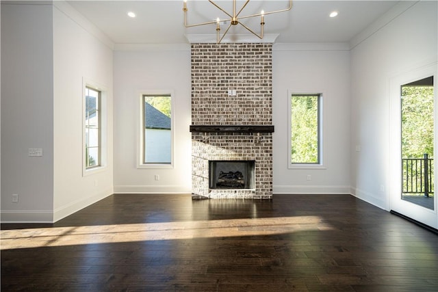 unfurnished living room with plenty of natural light, dark hardwood / wood-style flooring, crown molding, and a brick fireplace