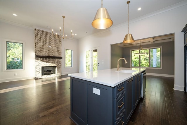 kitchen with a center island with sink, hanging light fixtures, and ornamental molding