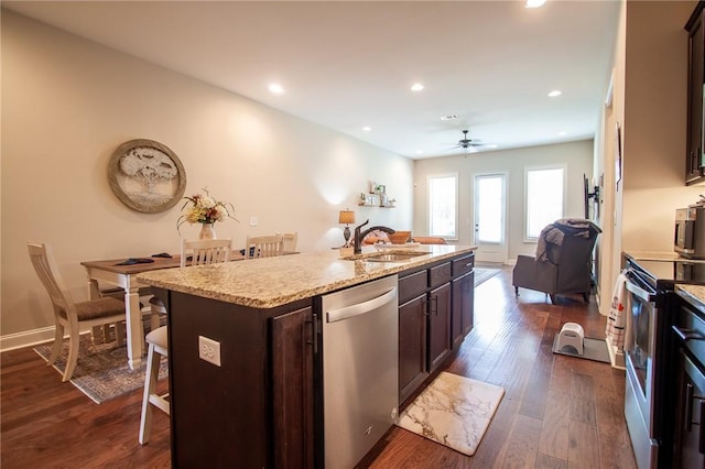 kitchen featuring appliances with stainless steel finishes, ceiling fan, a kitchen island with sink, sink, and a breakfast bar area