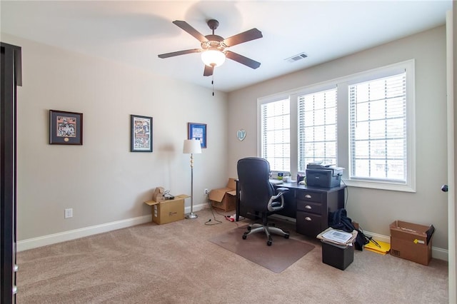 home office with plenty of natural light, ceiling fan, and light colored carpet