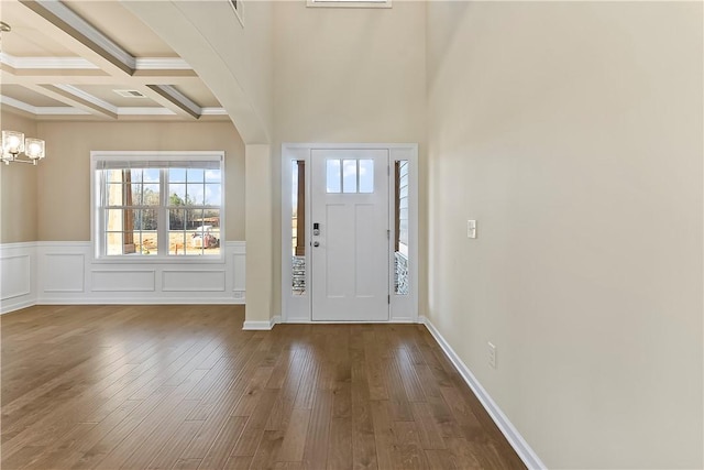 entryway featuring hardwood / wood-style flooring, coffered ceiling, a notable chandelier, and beamed ceiling