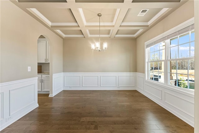 empty room with an inviting chandelier, coffered ceiling, dark hardwood / wood-style floors, and beam ceiling