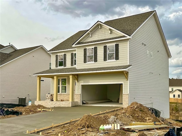 craftsman inspired home with central AC unit, a garage, brick siding, a shingled roof, and concrete driveway