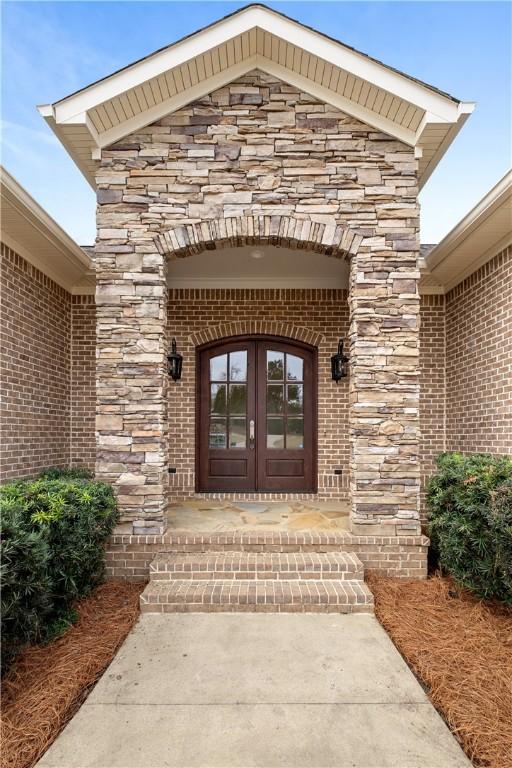 property entrance with brick siding, french doors, and stone siding