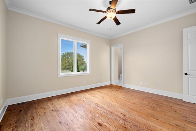 spare room with light wood finished floors, visible vents, a ceiling fan, ornamental molding, and baseboards