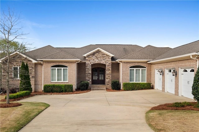 view of front of property featuring french doors, driveway, a garage, brick siding, and a shingled roof