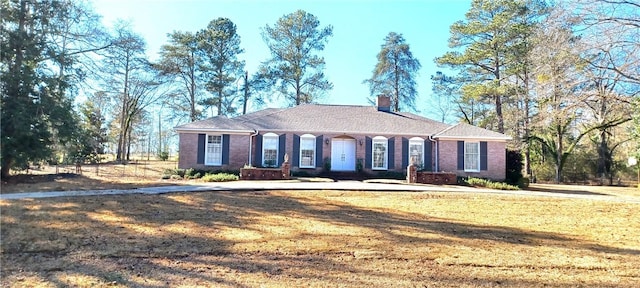 view of front facade featuring brick siding, a chimney, and a front yard