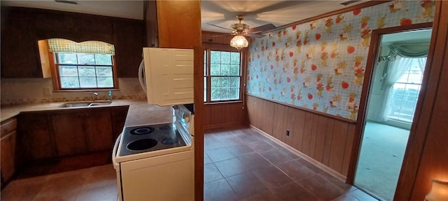 kitchen with wallpapered walls, a sink, light countertops, wainscoting, and white electric range