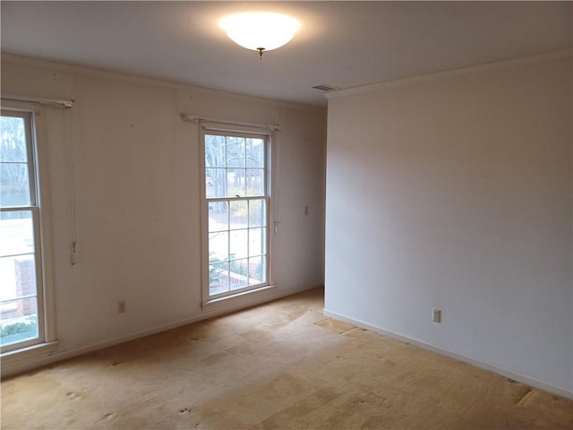 empty room with light carpet, visible vents, baseboards, and ornamental molding