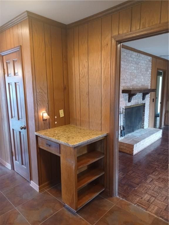 interior space with brown cabinets, open shelves, wooden walls, crown molding, and a brick fireplace