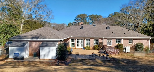 back of house with a patio, french doors, roof with shingles, brick siding, and a chimney